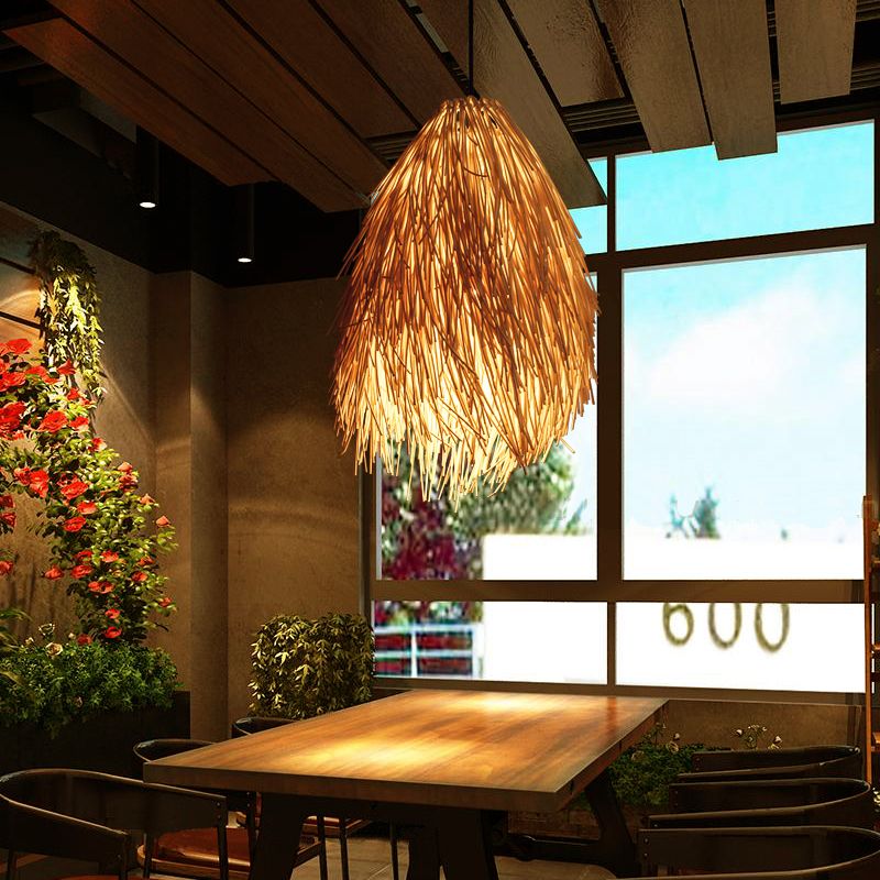 Muto woven rattan pendant illuminated above a dining table beside a window.