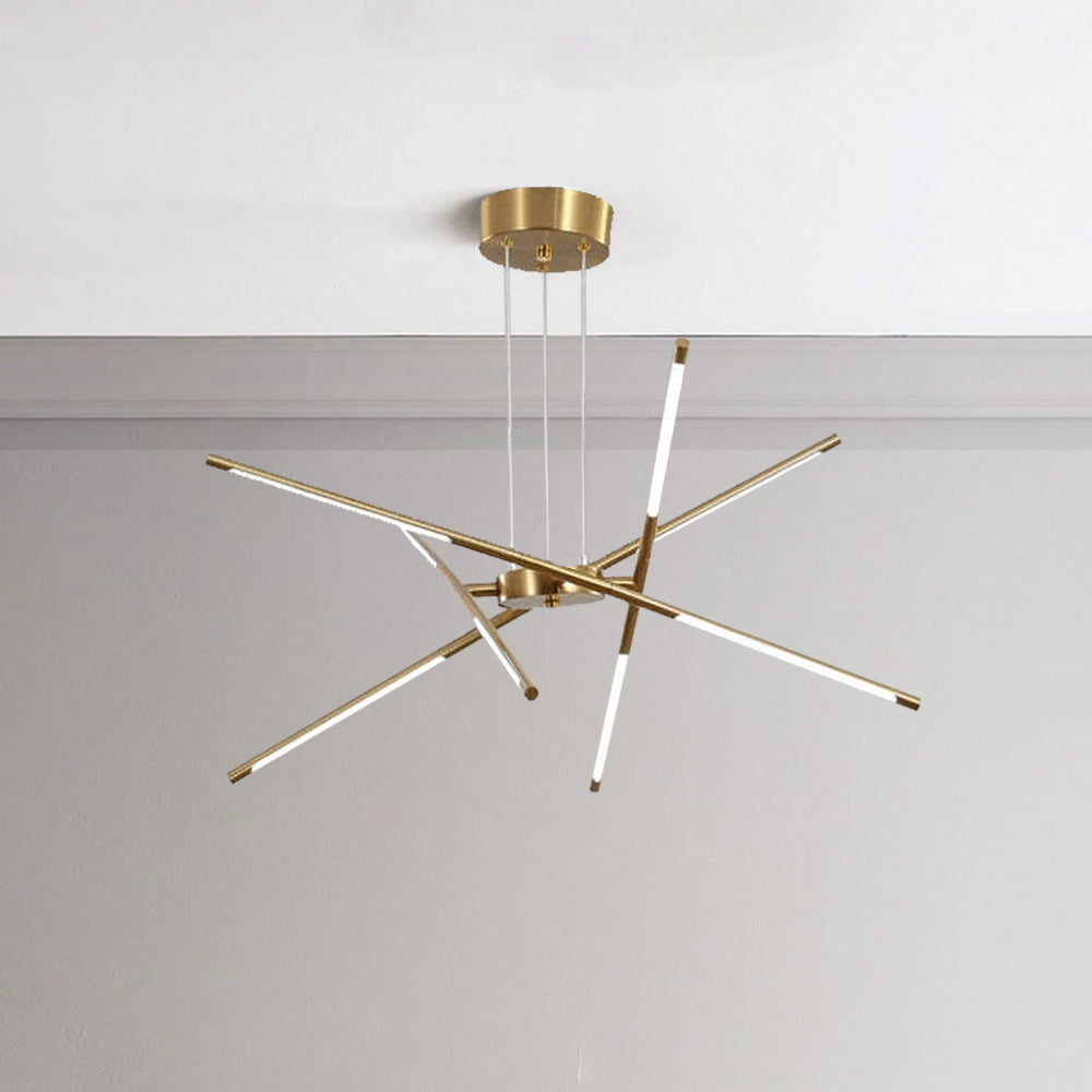 Gold eight-head Edge pendant against pale wall, with round canopy, suspension cables and one nearly vertical rod