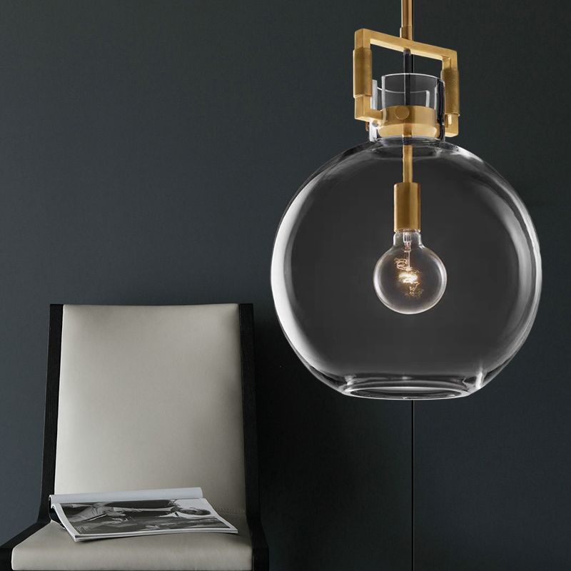 Cairns clear glass globe pendant near a pale chair with a magazine against a dark wall