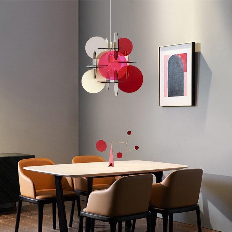 Morandi Red/Gray/White disc pendant above a dining table and chairs against a gray wall with framed artwork