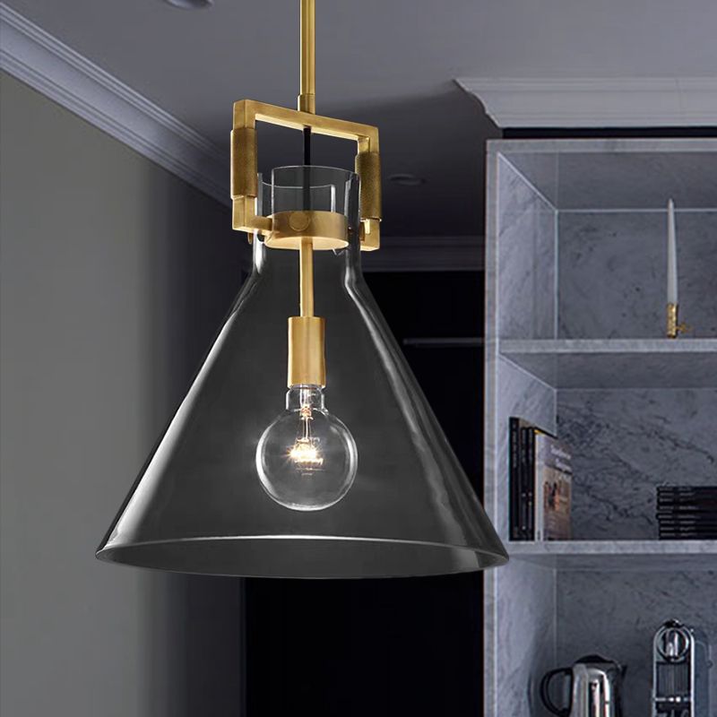 Close view of Cairns clear cone shade, brass-colour rectangular neck frame and visible bulb