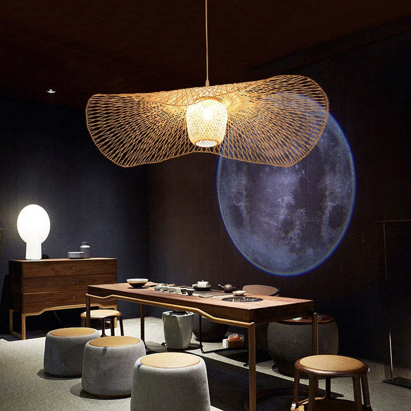 Wavy woven pendant above a wood tea table and stools with circular moon artwork behind