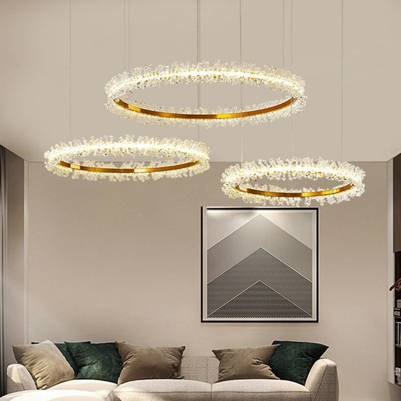 Kristy three-ring pendant light above a pale sofa with green cushions and geometric wall art.