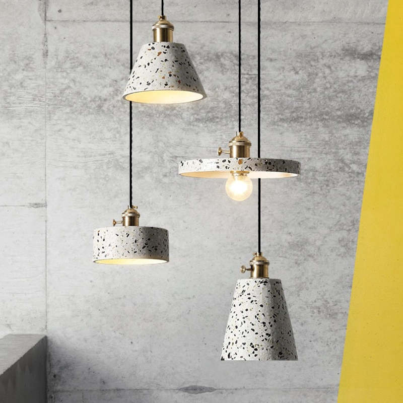 Speckled cone, disc and drum pendants with gold-tone holders against grey and yellow walls
