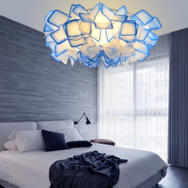 Blue-edged Bella acrylic flower pendant above a bed with gray walls and a sheer-curtained window