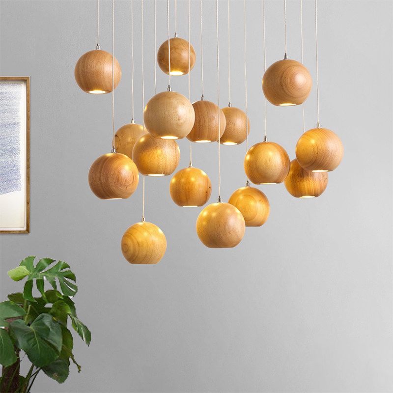 Large wooden globe pendant cluster in bright room beside plant