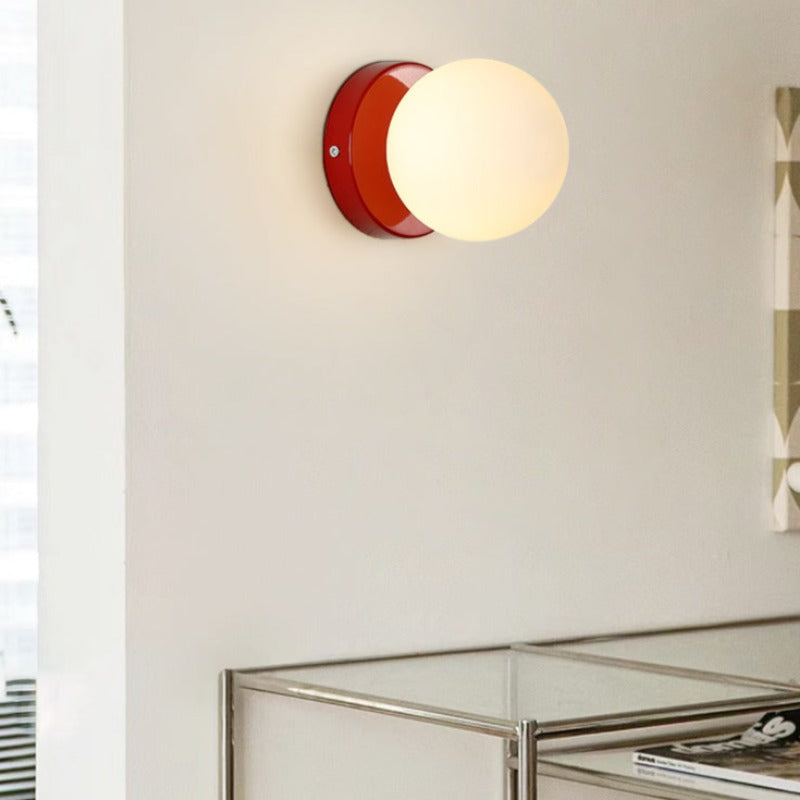 Red glass globe wall light above a small console