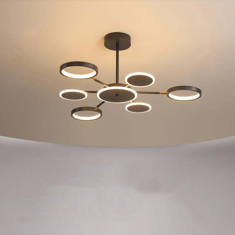 Six-arm radial fixture with illuminated rings, disc rims and a central disc under a plain ceiling
