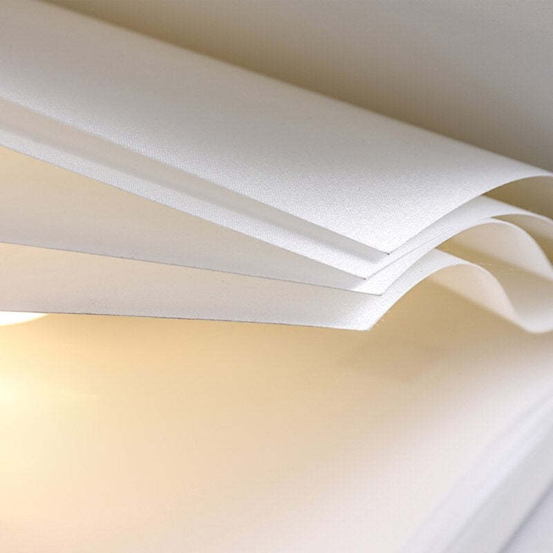 Close-up of White Sienna curved shade layers showing a fine fabric texture and warm-looking light between the panels