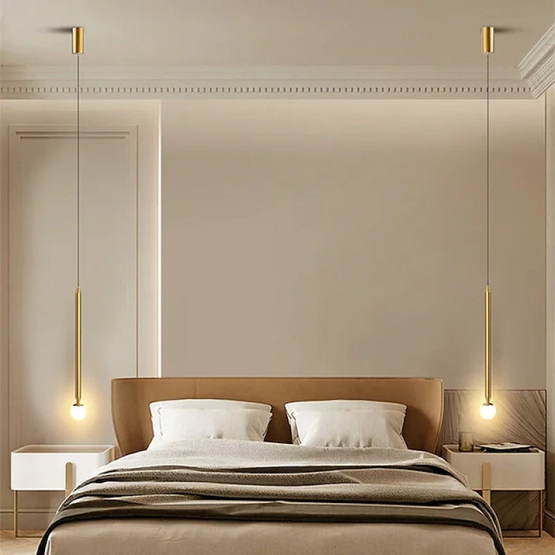 Two Carr Style B Gold globe-tip rod pendants framing a bed with a tan headboard and white nightstands, each with its own canopy