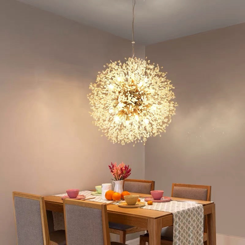 Gold Lili pendant above wood dining table with grey chairs, cups, oranges and pink flowers on a runner