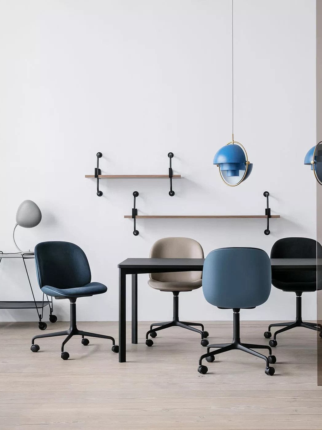 Blue metal pendant above an office meeting table