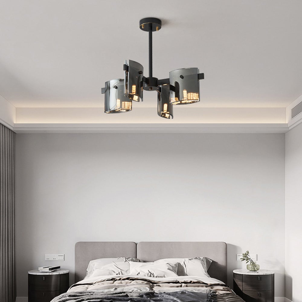 Black 4-head pendant above a grey upholstered bed, layered bedding and two dark round bedside cabinets