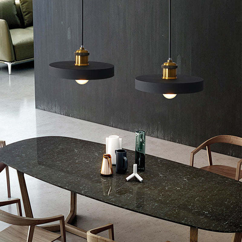 Two black Morandi shallow-disc pendants above a dark dining table.