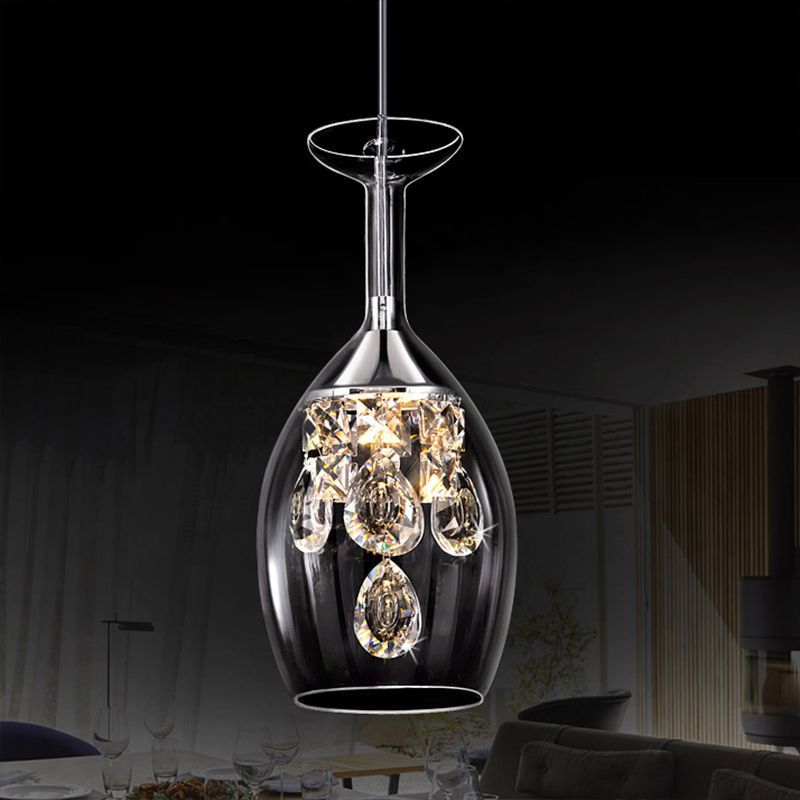 Elongated Kristy wine-glass-shaped shade and faceted drops suspended in front of a dining setting.