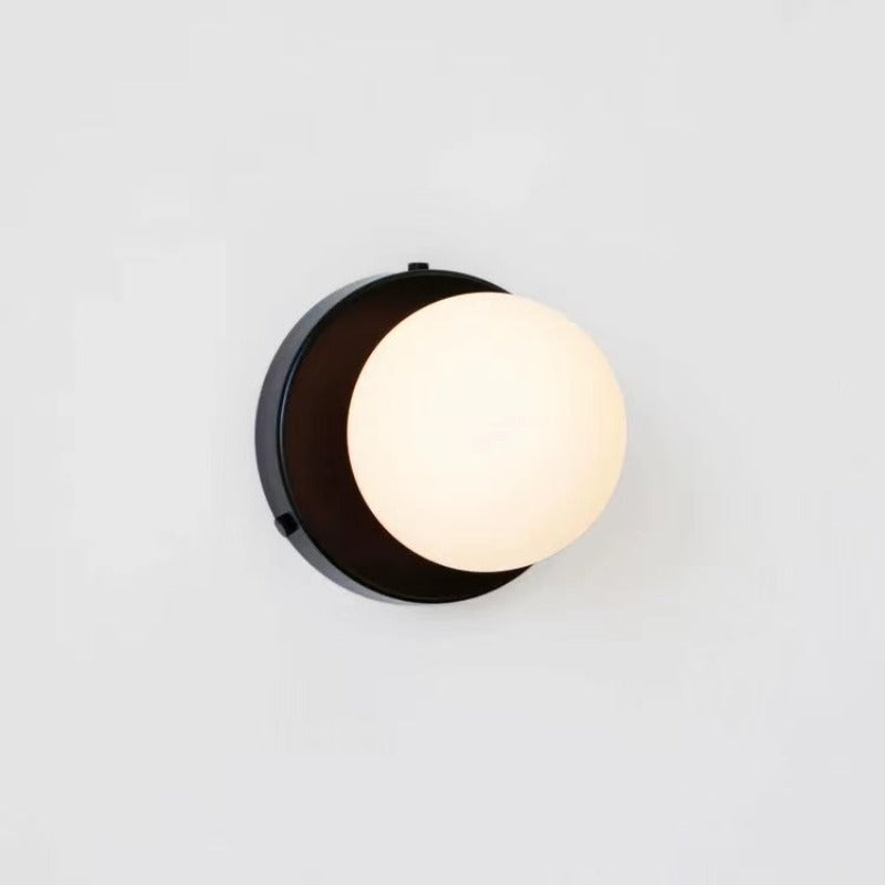 Black round wall plate behind white glass globe