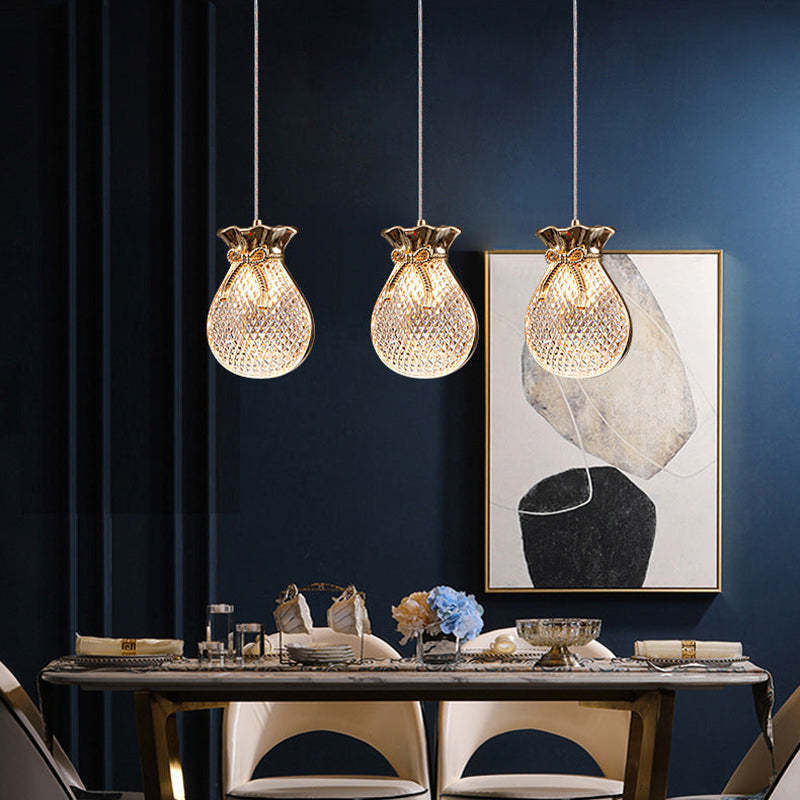 Three separate pouch-shaped Hailie pendants above a dining table.
