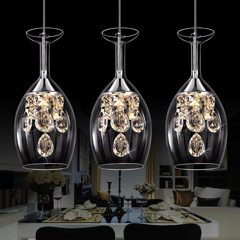 Three elongated Kristy inverted-wine-glass pendant lights with faceted drops above a dining setting.