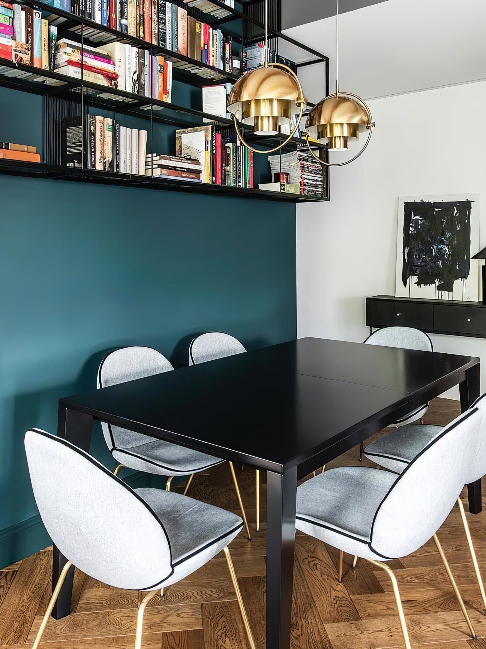 Copper-finish pendants above a dark table near bookshelves