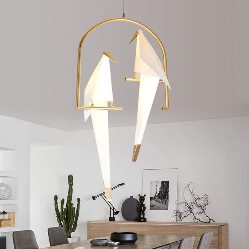 Arched two-bird pendant above a table and framed pictures.