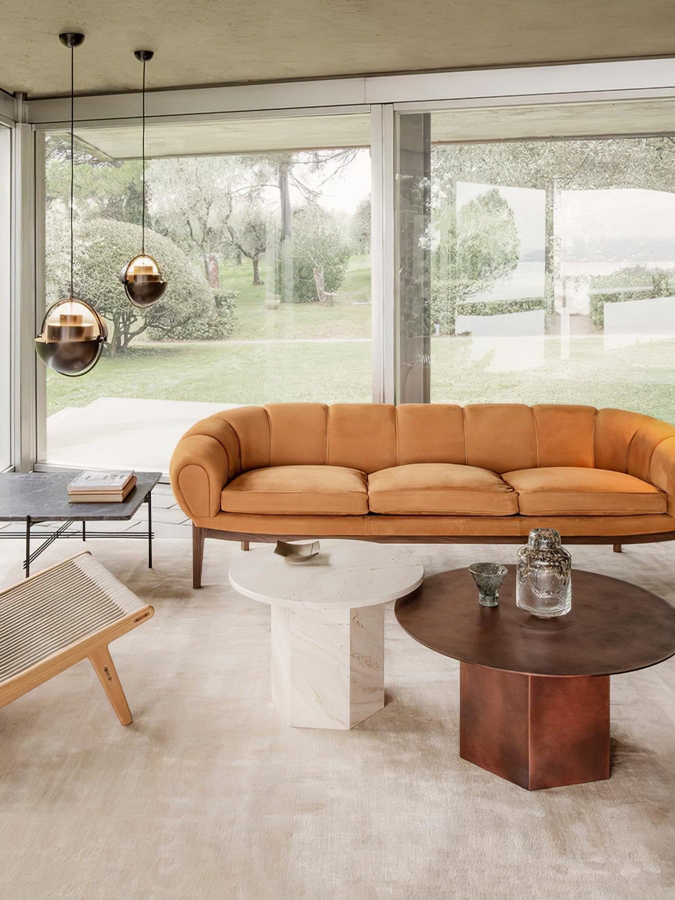Two pendants with dark outer shades and warm metallic interiors beside a living-room window