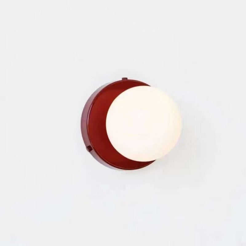 Red backplate and white globe wall sconce on pale background