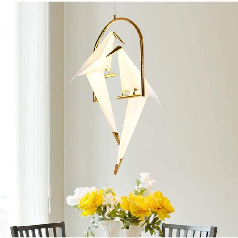 Two-bird pendant above a dining table with yellow flowers.