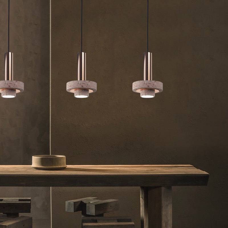Three speckled disc pendants above a wooden dining table and bowl against a dark wall