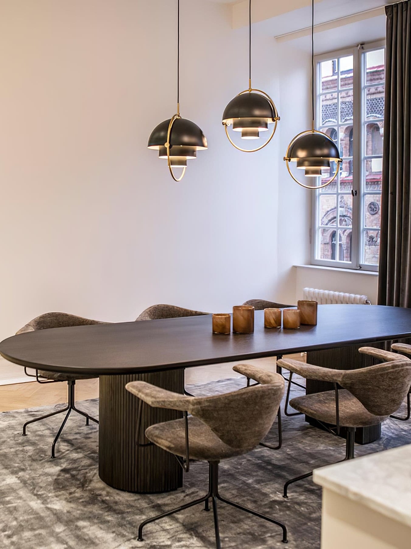 Three dark rotating-shade pendants over a dining table