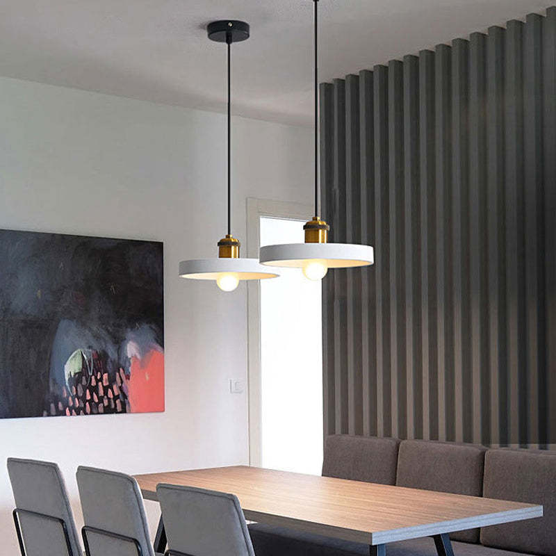 Two white Morandi disc pendants above a wooden dining table.