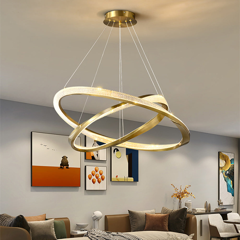 Gold rings crossing at angles above a living area with framed wall art and a sofa
