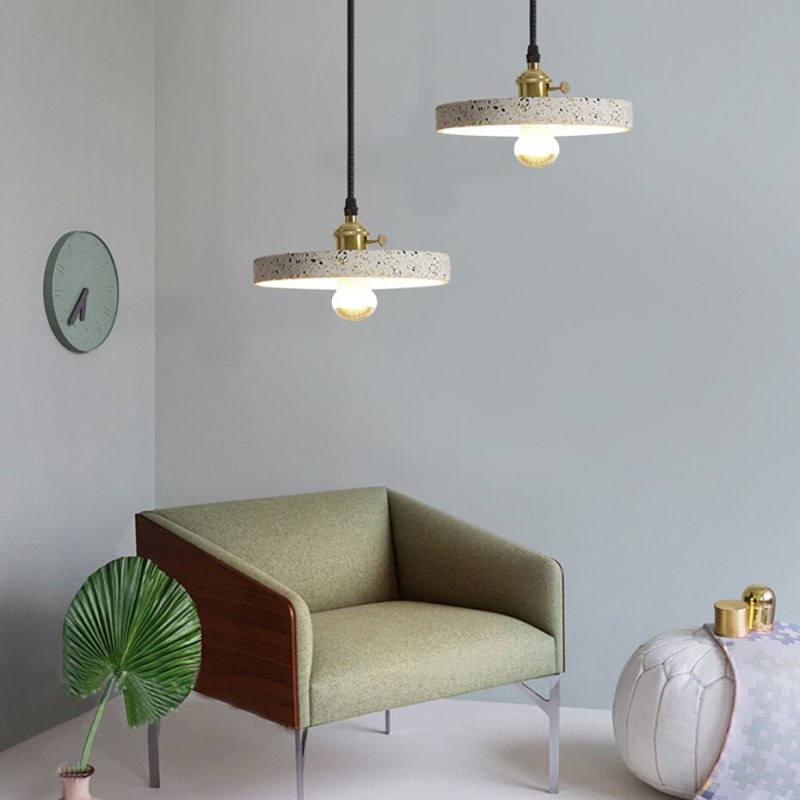 Two flat speckled disc pendants with exposed bulbs near a green chair and wall clock