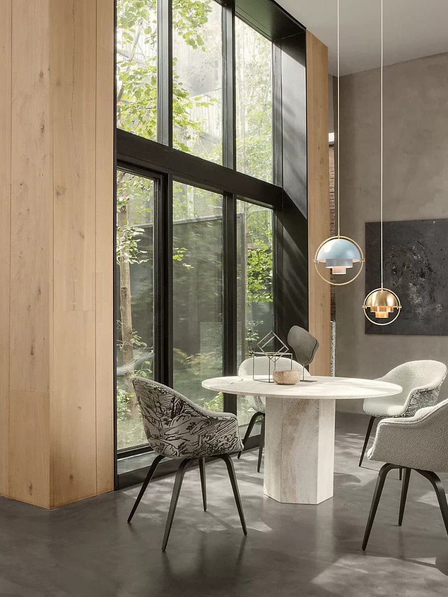 Two metal pendants above a table by tall windows