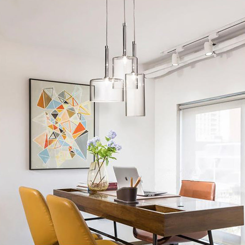 Three clear Kristy pendants above a wooden table with colourful chairs.