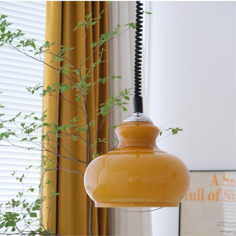 Orange glass dome pendant beside curtain and framed print