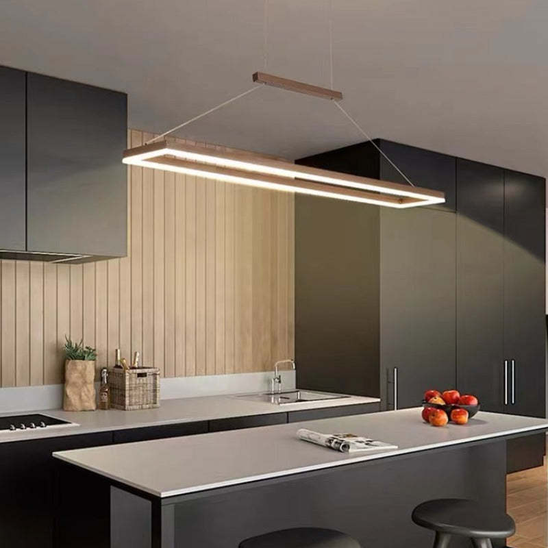 Coffee rectangular perimeter light over a grey kitchen island beside wood panels and dark cabinets