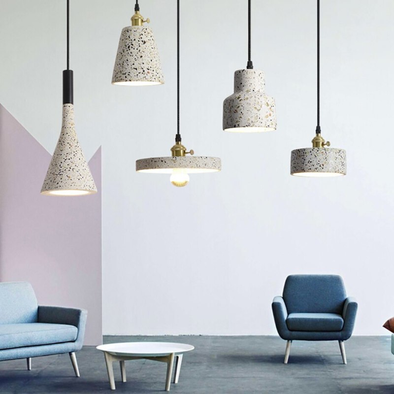 Wide view of five speckled pendant shapes over blue chairs and a coffee table