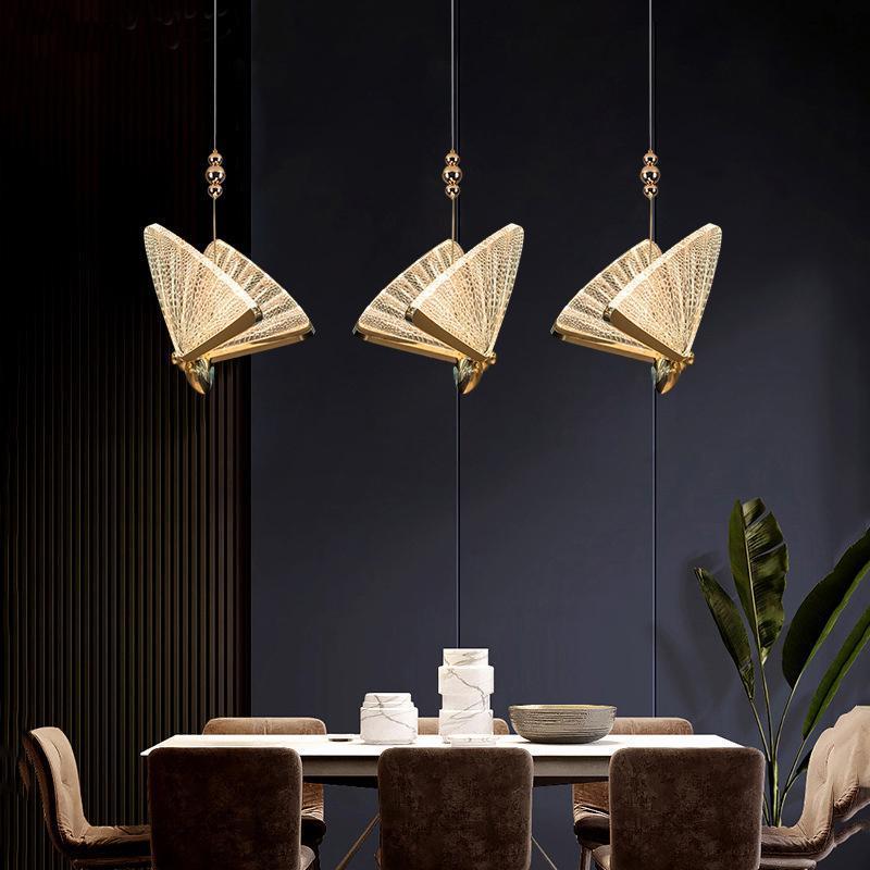 Three gold Kady butterfly pendants above a dining table