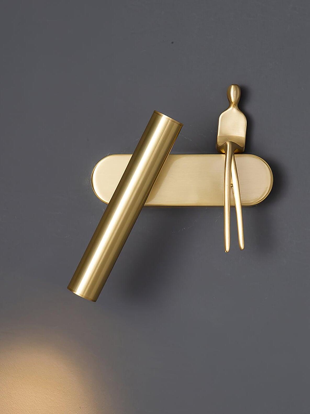 Front view of brass-coloured tilted tube and seated figure on a rounded rectangular wallplate