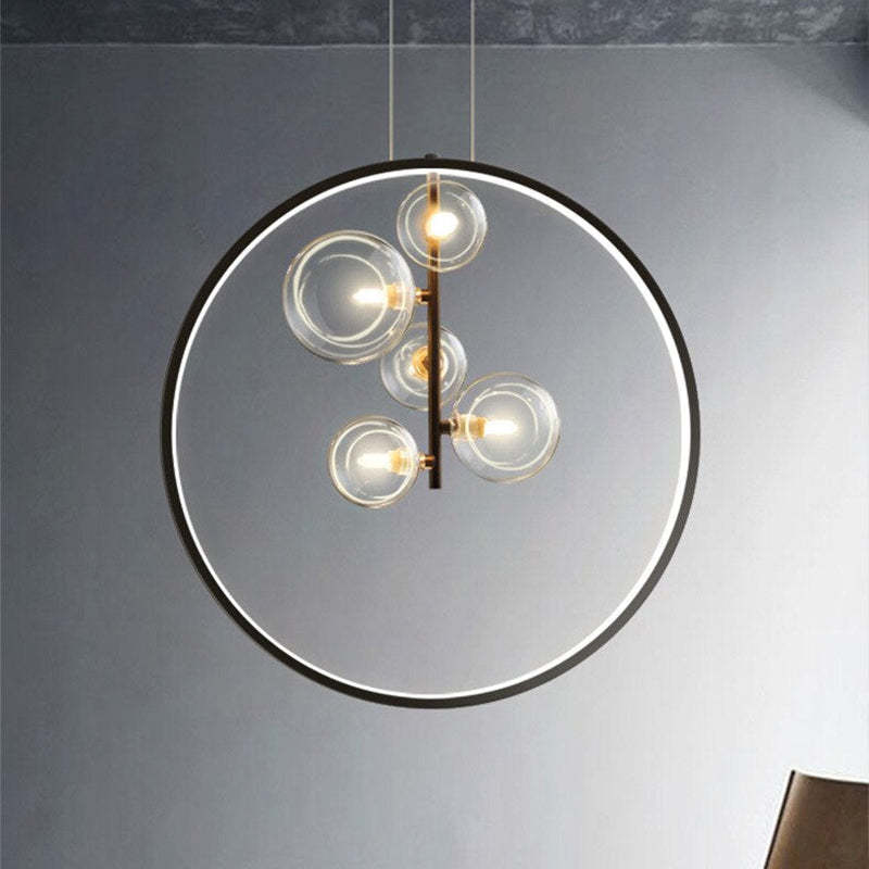 Five clear glass globes inside a lit black ring pendant against a grey wall