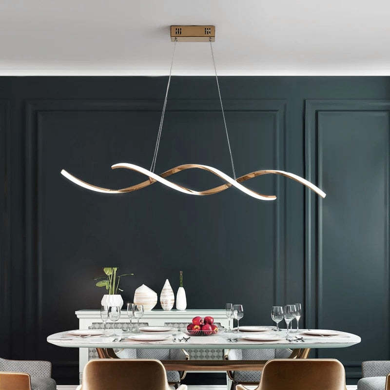 Illuminated gold Louise wave pendant over a dining table near a dark paneled wall