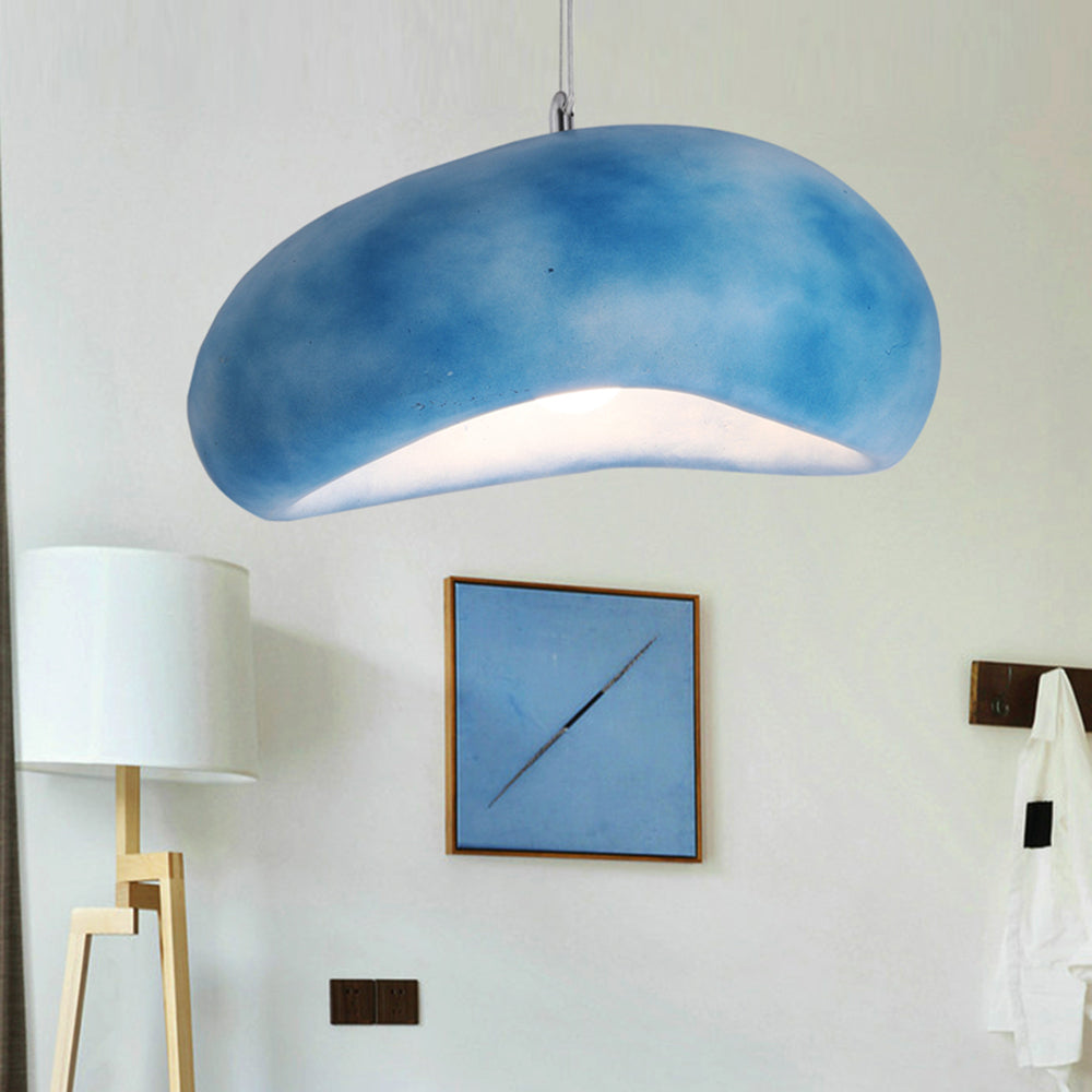 Cloud-mottled Blue Byers pendant light against a pale wall, above blue framed artwork beside a floor lamp.