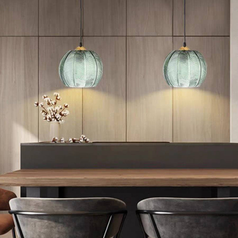 Two illuminated green glass pendants above dining bench seating.