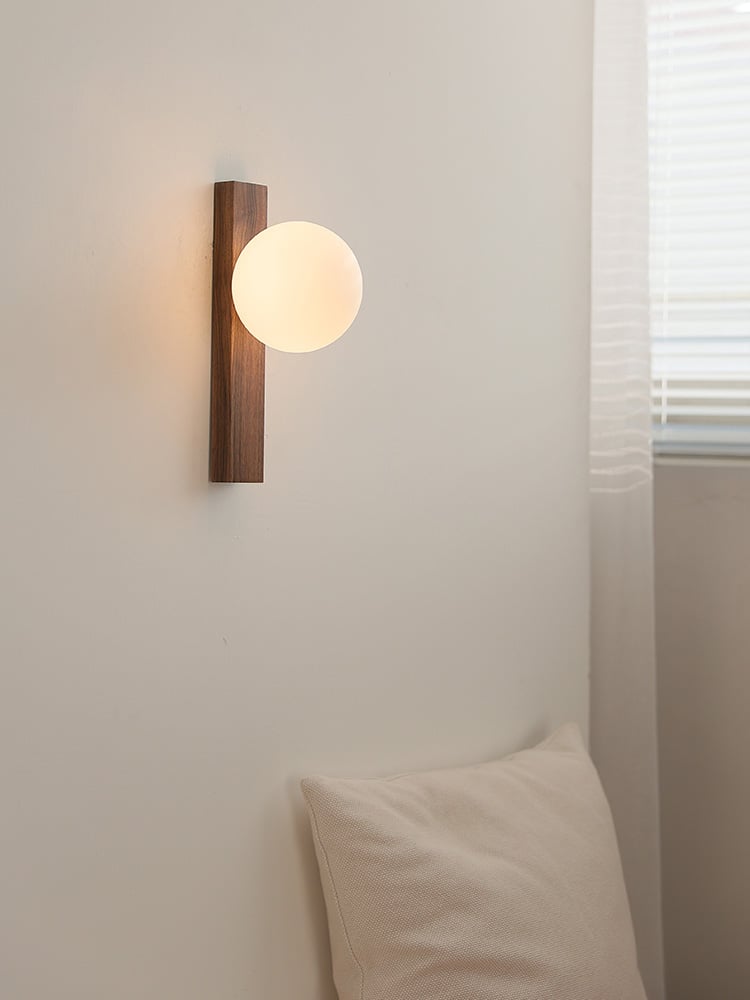 Lunaria walnut-bar wall light switched on beside a window