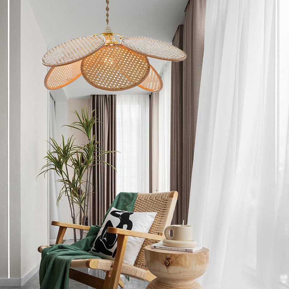 Woven petal pendant above a woven armchair with green throw beside curtains, a plant and a wooden side table