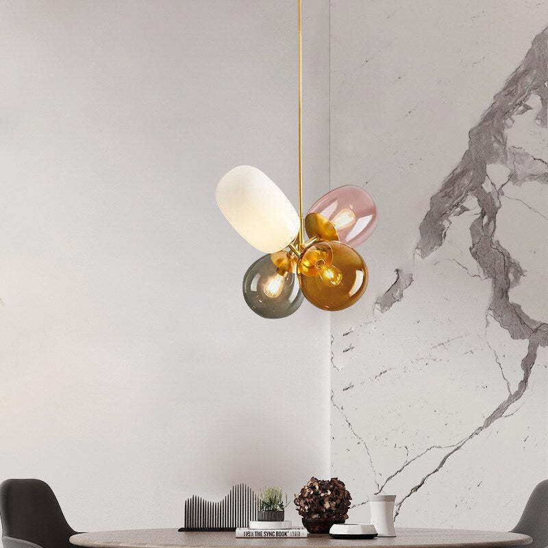 Multicoloured Morandi glass pendant illuminated beside a marble-pattern wall.