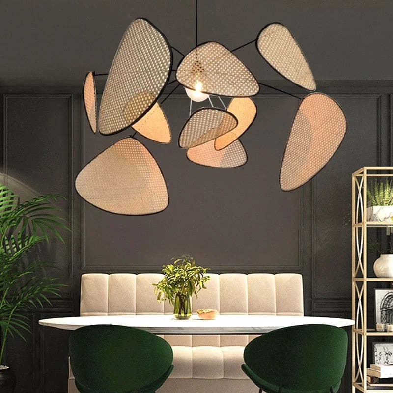 Rattan leaf pendant above a round dining table against dark wall