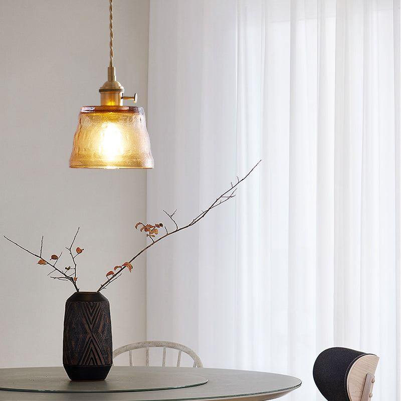 Brown glass pendant above round table and vase