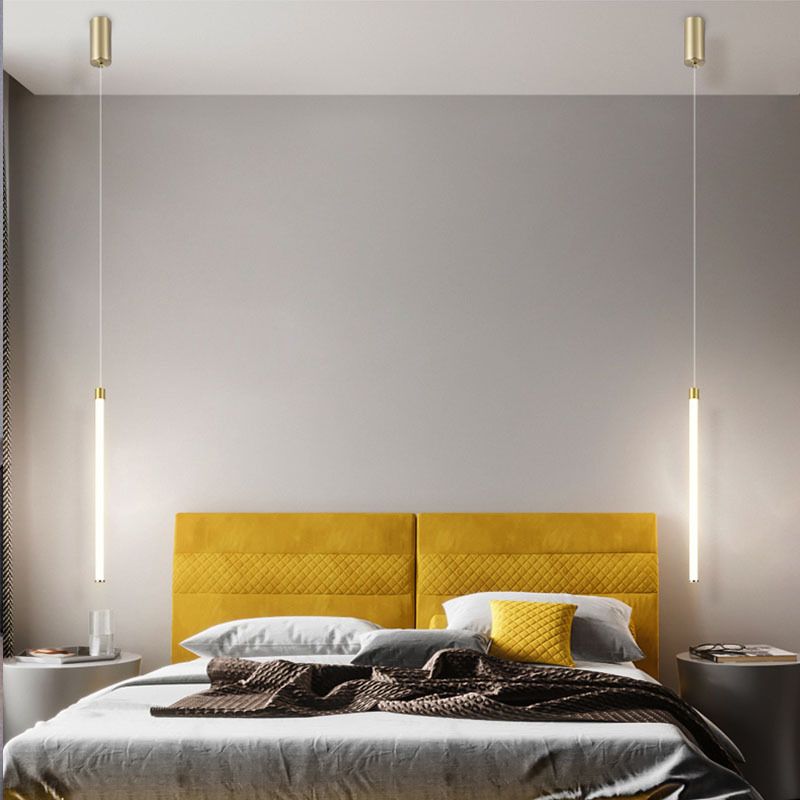 Two Edge tube pendants hanging beside a bed with a yellow headboard