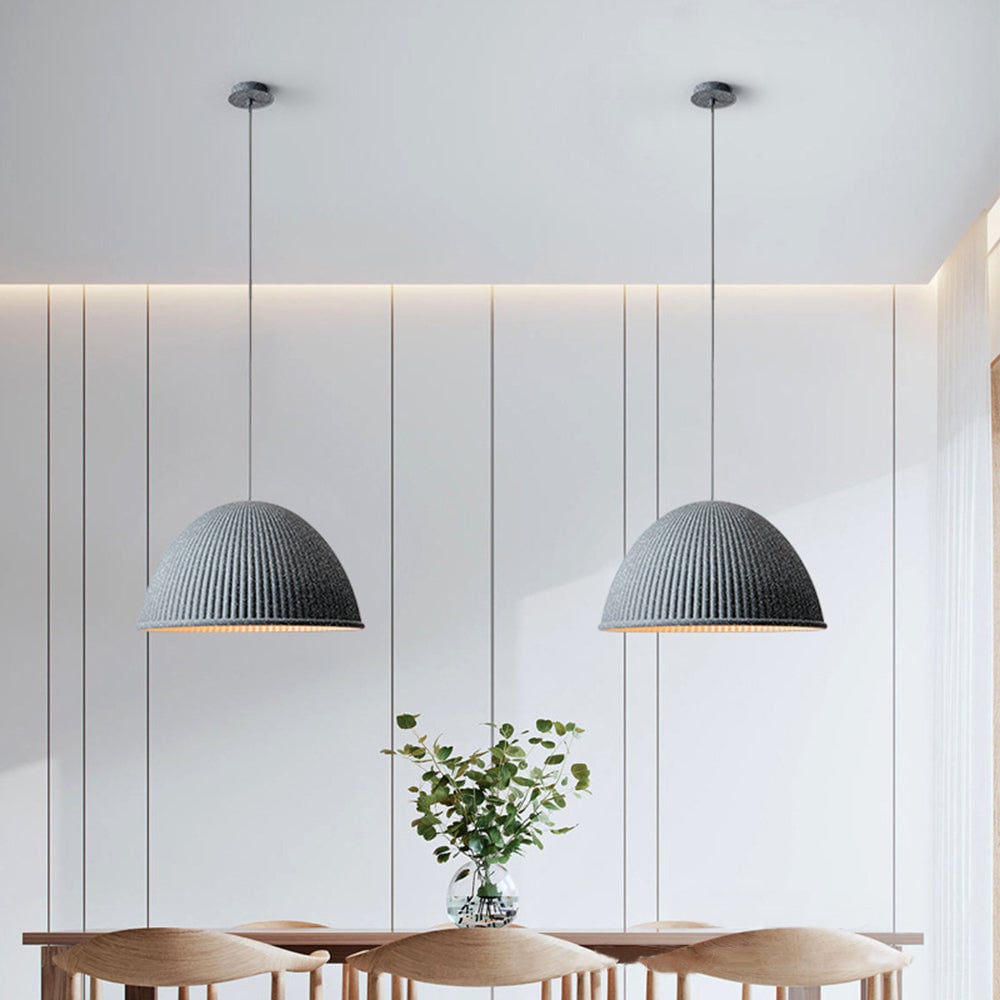 Two grey Morandi ribbed domes above a wood counter and curved wood chairs, with leafy branches in a vase and a panelled wall.
